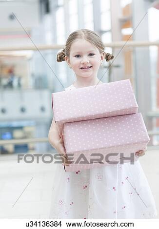 Young girl holding two gift wrapped boxes View Large Photo Image Picture - Young girl holding two gift wrapped boxes. Fotosearch