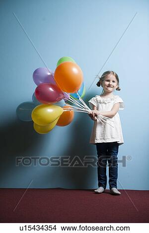 Picture - Young girl holds bunch of colorful balloons. Fotosearch