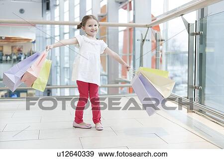 Young girl laden with paper shopping bags View Large Photo Image Stock Photo - Young girl laden with paper shopping bags. Fotosearch