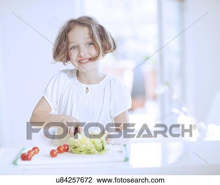 Stock Image - Young girl making a salad. Fotosearch