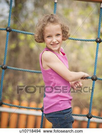 Picture - Young girl on climbing net turning to face camera. Fotosearch