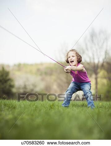 Stock Image - Young girl playing tug of war. Fotosearch