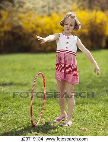 Picture - Young girl rolling hula hoop in park. Fotosearch