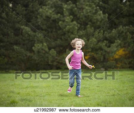 Stock Photo - Young girl running through park in summer. Fotosearch