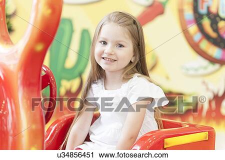 Young girl sitting on childrens car ride View Large Photo Image Stock Image - Young girl sitting on childrens car ride. Fotosearch