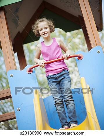 Young girl standing at top of slide in playground View Large Photo Image Stock Image - Young girl standing at top of slide in playground. Fotosearch