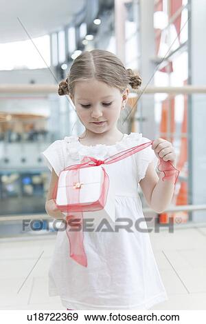 Young girl unwrapping ribbon on present View Large Photo Image Stock Photo - Young girl unwrapping ribbon on present. Fotosearch