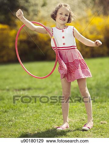 Stock Photo - Young girl using hula hoop on arm in a park. Fotosearch