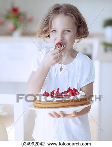 Stock Image - Young girl with cake and strawberries. Fotosearch