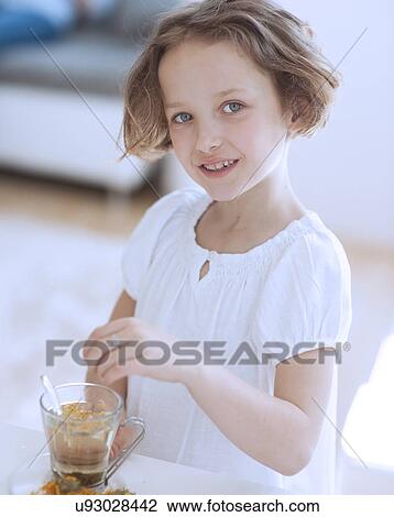 Stock Image - Young girl with cup of tea and flowers. Fotosearch