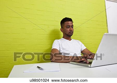 Young Indian man working at his computer View Large Photo Image Picture - Young Indian man working at his computer. Fotosearch