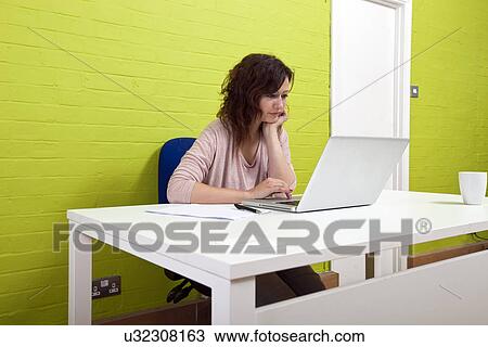 Young woman working at her desk View Large Photo Image Stock Image - Young woman working at her desk. Fotosearch