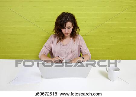 Stock Photo - Young woman working at her laptop on a clean desk. Fotosearch