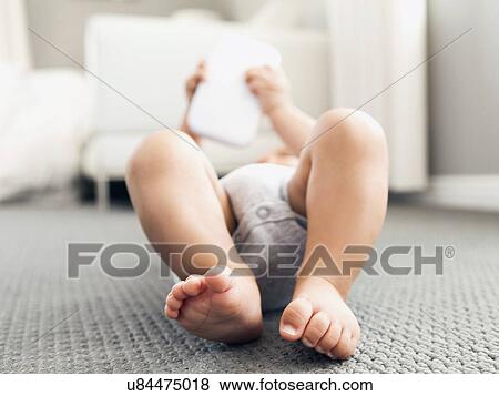 Stock Photo - Baby boy (2-5 months) lying on floor playing. Fotosearch