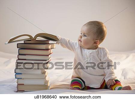 Baby girl (6-11 months) sitting in bed with stack of books View Large Photo Image Stock Image - Baby girl (6-11 months) sitting in bed with stack of books. Fotosearch