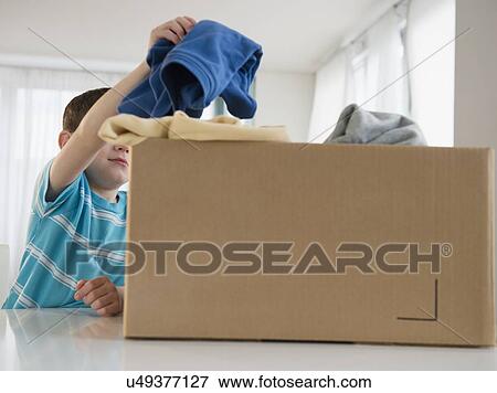 Stock Photo - Boy (4-5) putting clothing into box. Fotosearch