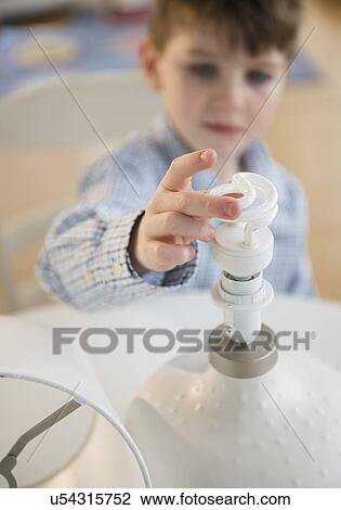 Stock Image - Boy (4-5) touching energy efficient lightbulb. Fotosearch
