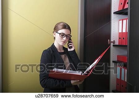Businesswoman reading files and talking on cell phone View Large Photo Image Stock Photo - Businesswoman reading files and talking on cell phone. Fotosearch