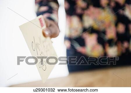 Stock Image - Close up of woman's hand holding letter. Fotosearch