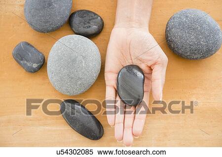 Stock Photography - Close up of woman's hand holding pebble. Fotosearch