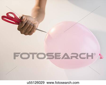 Close up of woman's hand popping balloon with scissors View Large Photo Image Stock Photo - Close up of woman's hand popping balloon with scissors. Fotosearch