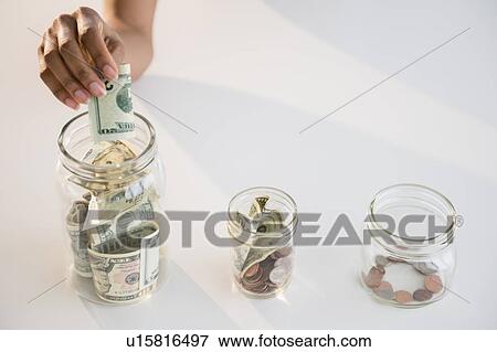 Close up of woman's hand putting money into jar View Large Photo Image Stock Photo - Close up of woman's hand putting money into jar. Fotosearch