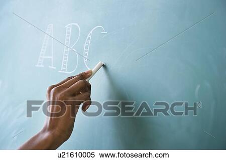Stock Photography - Close up of woman's hand writing alphabet on blackboard. Fotosearch