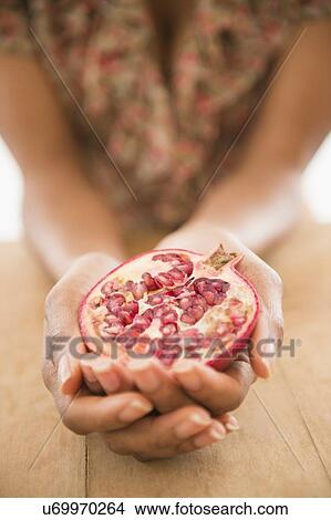 Picture - Close up of woman's hands holding pomegranate fruit. Fotosearch