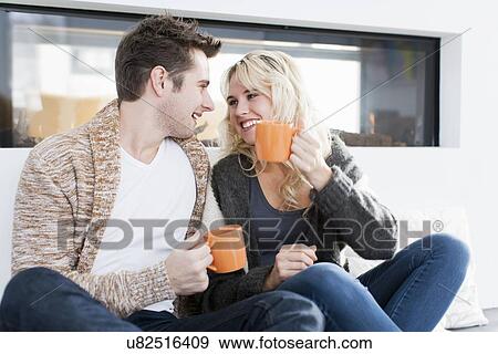 Stock Photo - Couple drinking coffee in front of fireplace. Fotosearch
