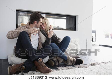 Stock Image - Couple embracing in front of fireplace. Fotosearch