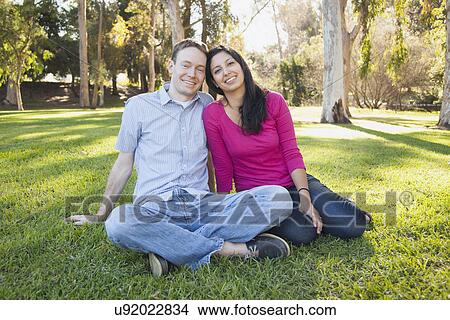 Couple sitting on grass in park View Large Photo Image Picture - Couple sitting on grass in park. Fotosearch