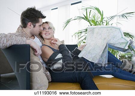 Couple sitting on sofa and reading map View Large Photo Image Stock Photograph - Couple sitting on sofa and reading map. Fotosearch
