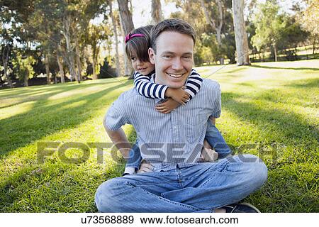 Stock Photo - Daughter (4-5 years) embracing her father in park. Fotosearch