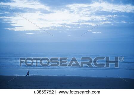 Distant view of woman running along beach View Large Photo Image Stock Image - Distant view of woman running along beach. Fotosearch
