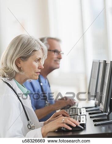 Stock Photo - Female and male doctors working at computers. Fotosearch