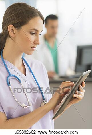 Stock Image - Female and male nurses working at nurse's station in hospital. Fotosearch