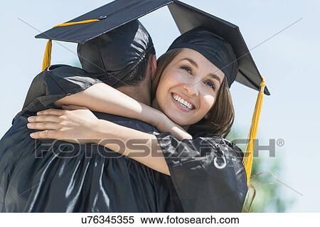Stock Photography - Female and male students embracing on graduation ceremony. Fotosearch