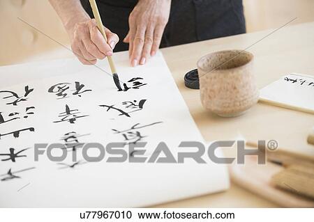 Stock Image - Female hands and japanese calligraphy. Fotosearch