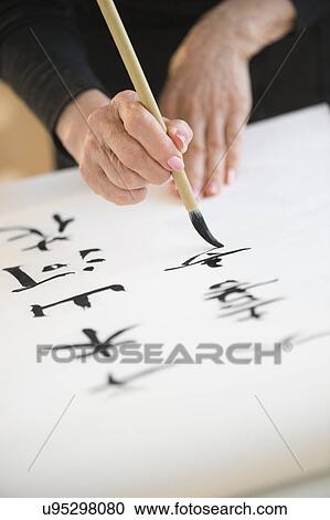 Stock Image - Female hands and japanese calligraphy. Fotosearch