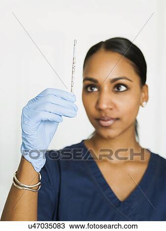 Female nurse looking at thermometer View Large Photo Image Stock Image - Female nurse looking at thermometer. Fotosearch