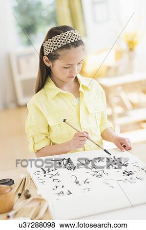 Stock Photo - Girl (8-9) painting japanese symbols. Fotosearch