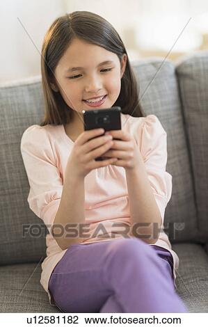 Girl (8-9) sitting on sofa and using cell phone View Large Photo Image Stock Image - Girl (8-9) sitting on sofa and using cell phone. Fotosearch