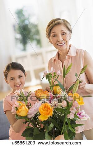 Granddaughter (8-9) and grandmother arranging flowers at home View Large Photo Image Stock Photo - Granddaughter (8-9) and grandmother arranging flowers at home. Fotosearch