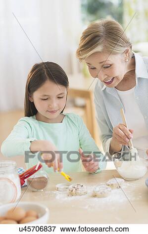Stock Photo - Granddaughter (8-9) cooking with grandmother. Fotosearch