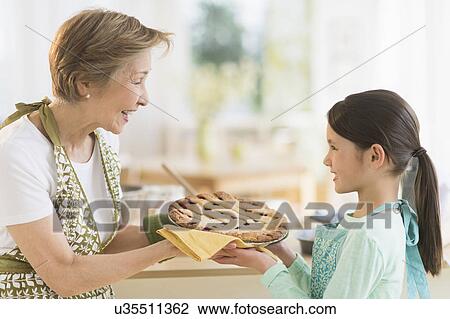 Grandmother and granddaughter (8-9) holding freshly baked pie View Large Photo Image Stock Image - Grandmother and granddaughter (8-9) holding freshly baked pie. Fotosearch