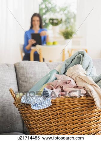 Laundry basket on sofa and woman in background View Large Photo Image Stock Photography - Laundry basket on sofa and woman in background. Fotosearch