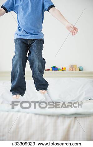 Low section of boy (4-5) jumping on bed View Large Photo Image Stock Photo - Low section of boy (4-5) jumping on bed. Fotosearch