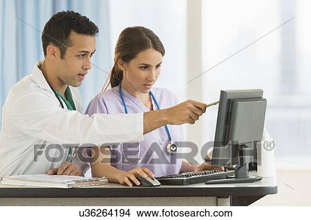 Male and female nurses working at nurse's station in hospital View Large Photo Image Picture - Male and female nurses working at nurse's station in hospital. Fotosearch