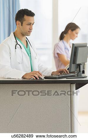 Male and female nurses working at nurse's station in hospital View Large Photo Image Stock Photo - Male and female nurses working at nurse's station in hospital. Fotosearch
