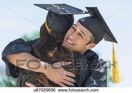 Stock Photograph - Male and female students embracing on graduation ceremony. Fotosearch